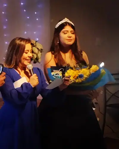 15 anos: debutante de vestido azul com tiara, cortina de luzes, buque. Festa de 15 anos realizada no Espaço Comemora em 2023