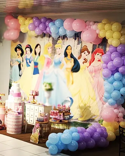 princesas Disney com arco pastel; salao montado. Festa realizada no Espaço Comemora em 2023