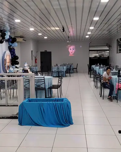 salao montado em azul-claro com painel redondo e projecao; 3 fotos. Festa realizada no Espaço Comemora em 2023