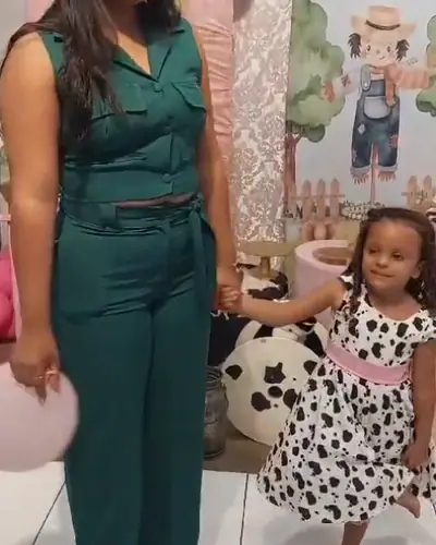 mae e filha com vestido de estampa de vaca diante do painel da fazendinha. Festa realizada no Espaço Comemora em 2023
