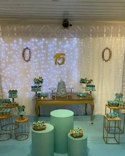 15 anos: cortina de luzes, molduras douradas, paleta verde-agua e dourado; 3 fotos. Festa de 15 anos realizada no Espaço Comemora em 2024