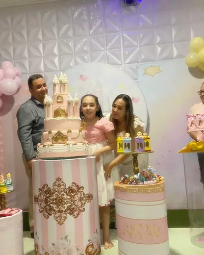 castelo em rosa e dourado listrado; familia com a aniversariante. Festa realizada no Espaço Comemora em 2024