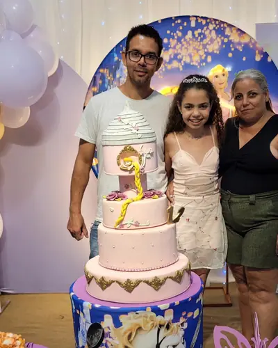 familia diante do painel da Rapunzel; lilas, dourado e azul. Festa realizada no Espaço Comemora em 2024