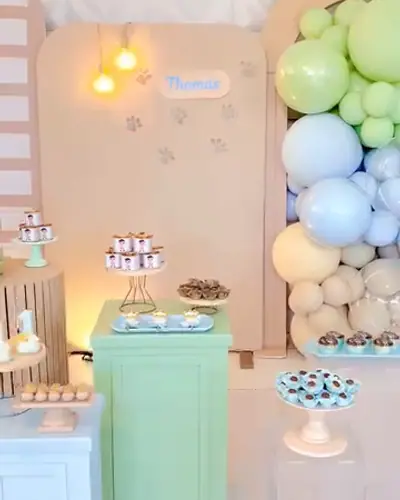 primeiro aninho do Thomas com o caozinho; pastel verde e azul, patinhas, escada de madeira. Festa realizada no Espaço Comemora em 2025