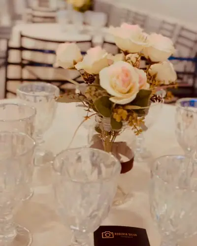 CASAMENTO: mesa posta com flores brancas e tacas; legenda 'Dia de sim'. Festa realizada no Espaço Comemora em 2025