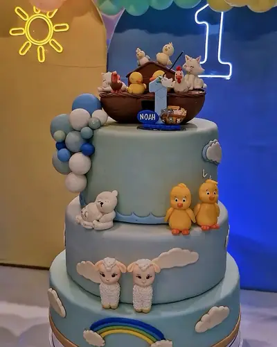 bolo azul 3 andares com arca de Noe, animais, arco-iris, sol neon, neon 1. Festa realizada no Espaço Comemora em 2026