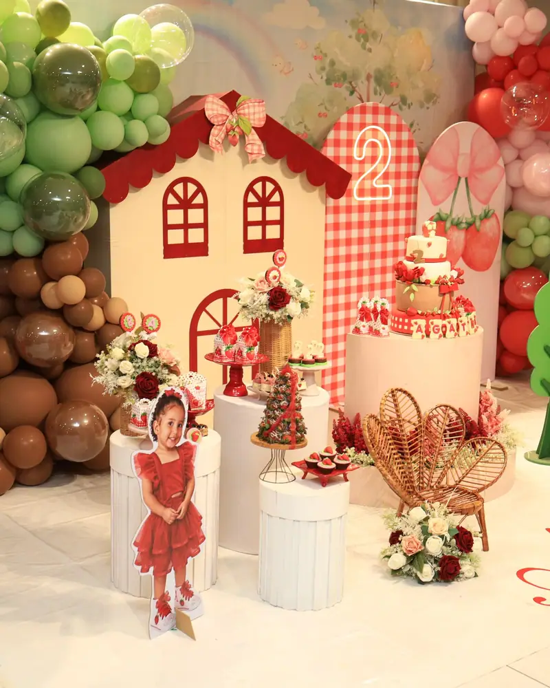 Festa tema morango: casinha vermelha e branca, balões verdes e marrons e mesa de doces